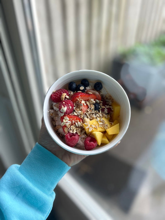 breakfast bowl: oats sprinkled with granola and seeds, mango, raspberry, blueberry, strawberry