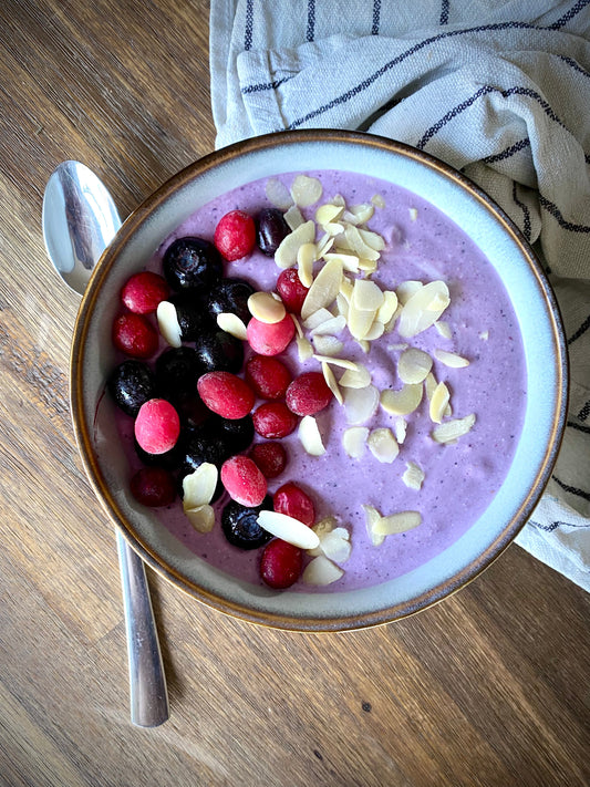 purple smoothie bowl sprinkled with berries and almond flakes