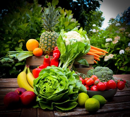 Colorful vegetables and fruits on the wood table: ananas, cauliflower, limes, bananas, lettuce, paprika, leek, broccoli, carrot, tomatoes
