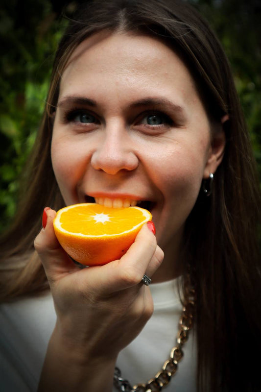 Woman in a white t-shirt bites an orange