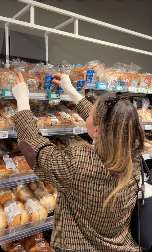 A woman in a supermarket is comparing bread.